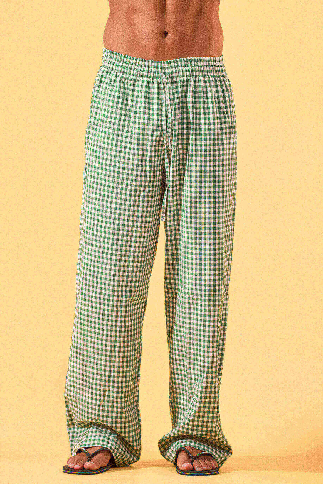 a man wearing a white tee and green and white checkered lounge pants