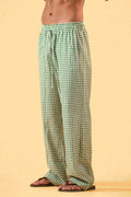 a man wearing a white tee and green and white checkered lounge pants