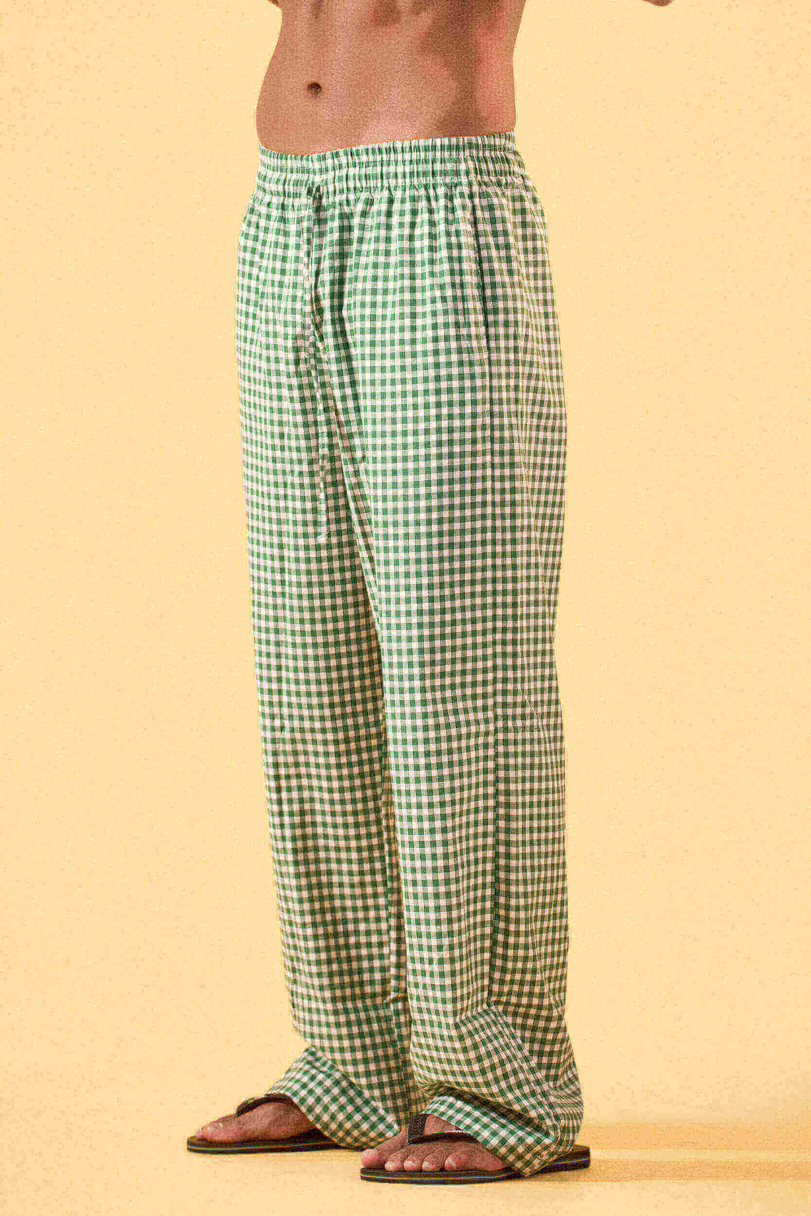 a man wearing a white tee and green and white checkered lounge pants