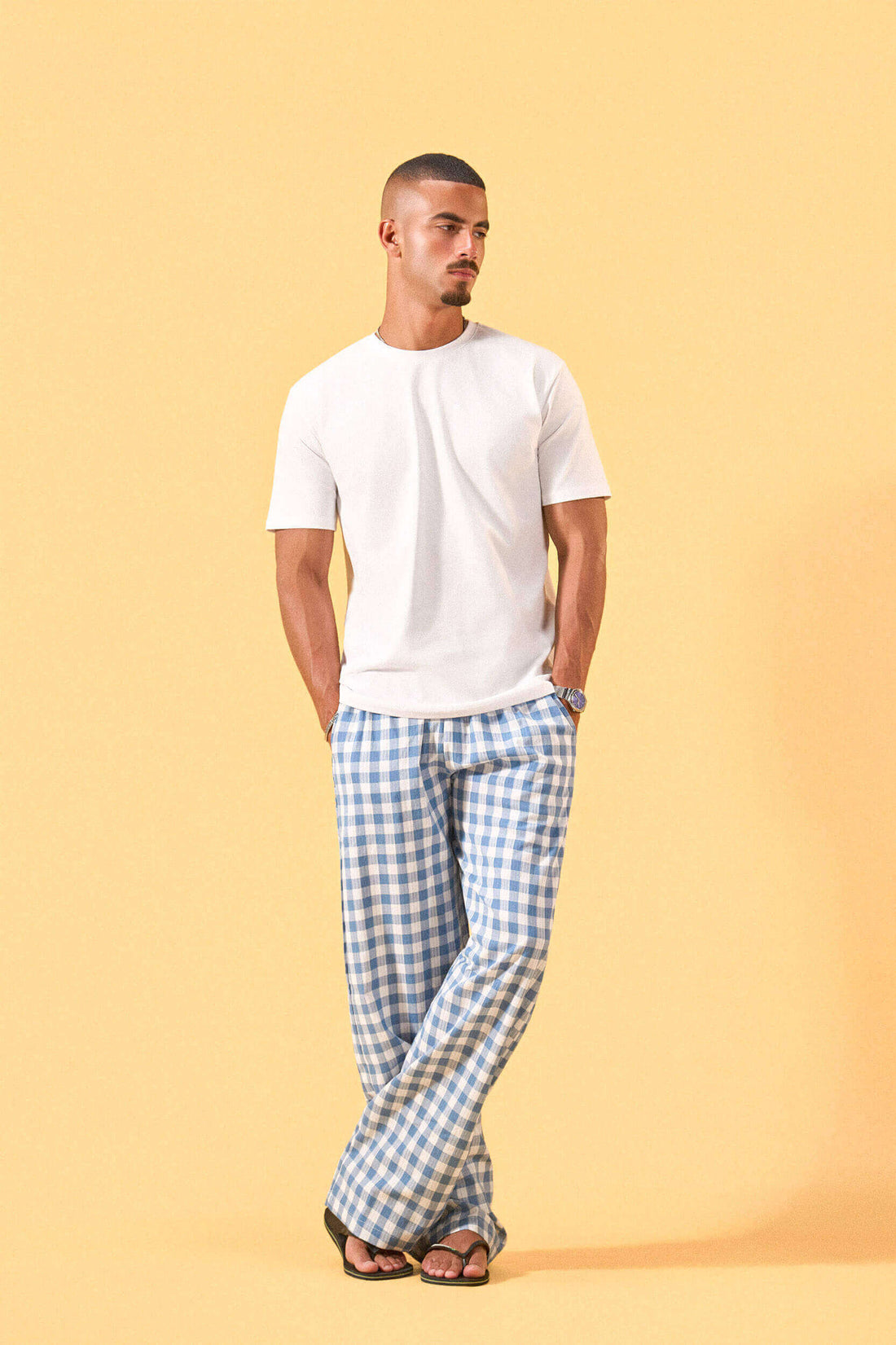 a man wearing a white tee and blue and white checkered lounge pants