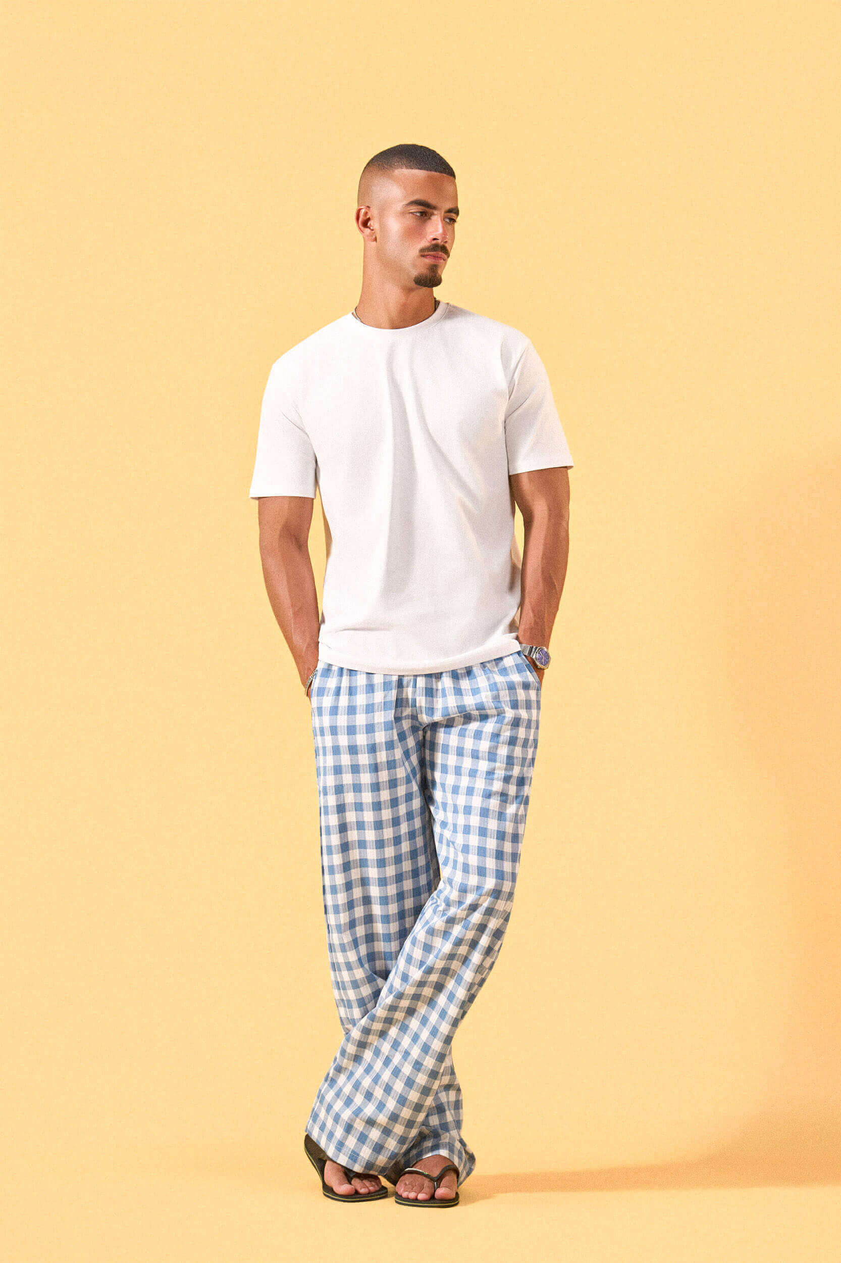a man wearing a white tee and blue and white checkered lounge pants