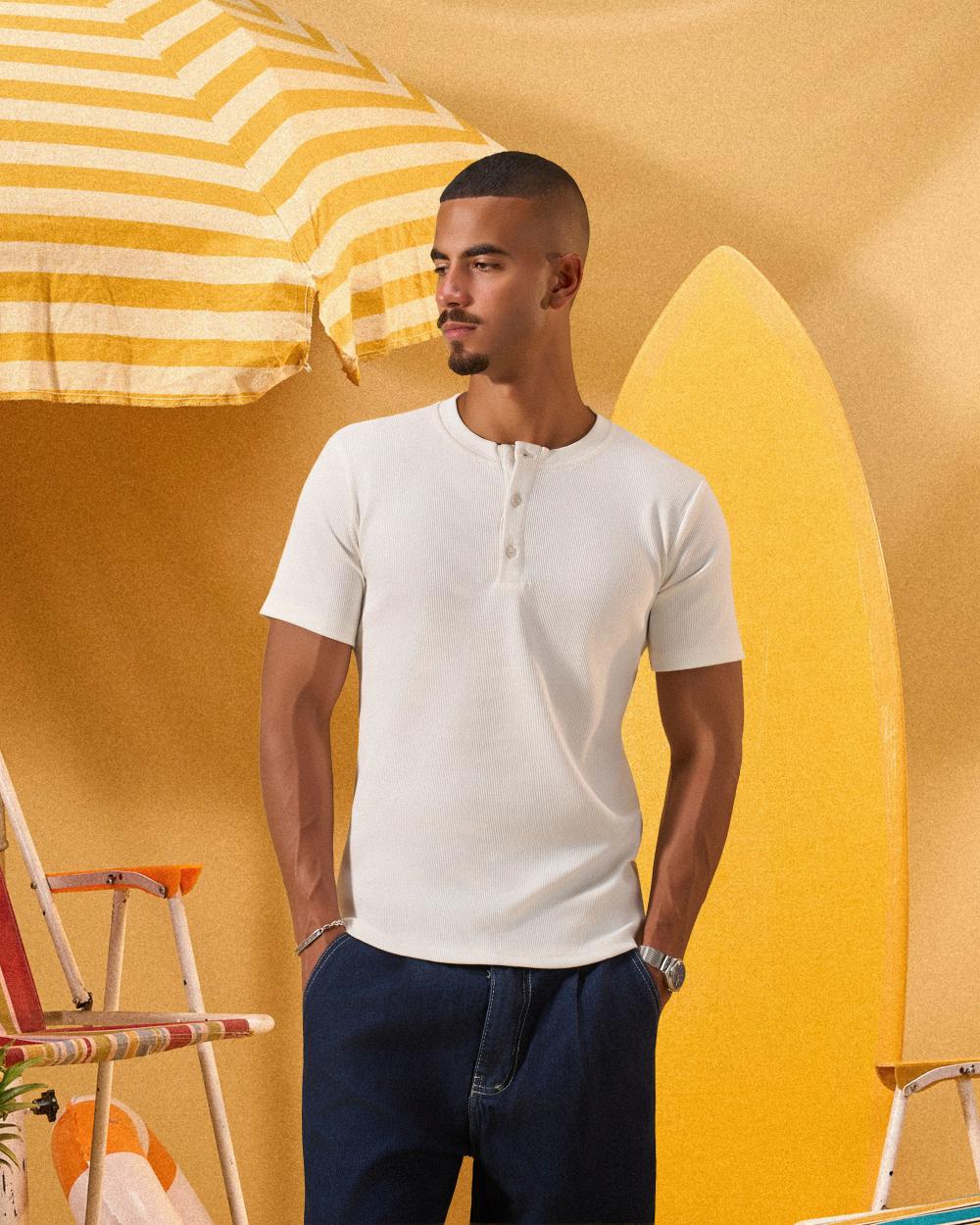 a male wearing  an off white t-shirt with buttons at the top that is a ribbed material 