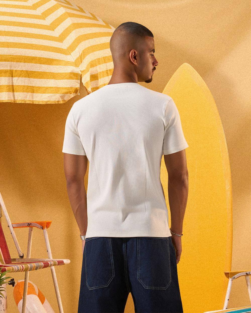 a male wearing  an off white t-shirt with buttons at the top that is a ribbed material 
