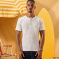 a male wearing  an off white t-shirt with buttons at the top that is a ribbed material 