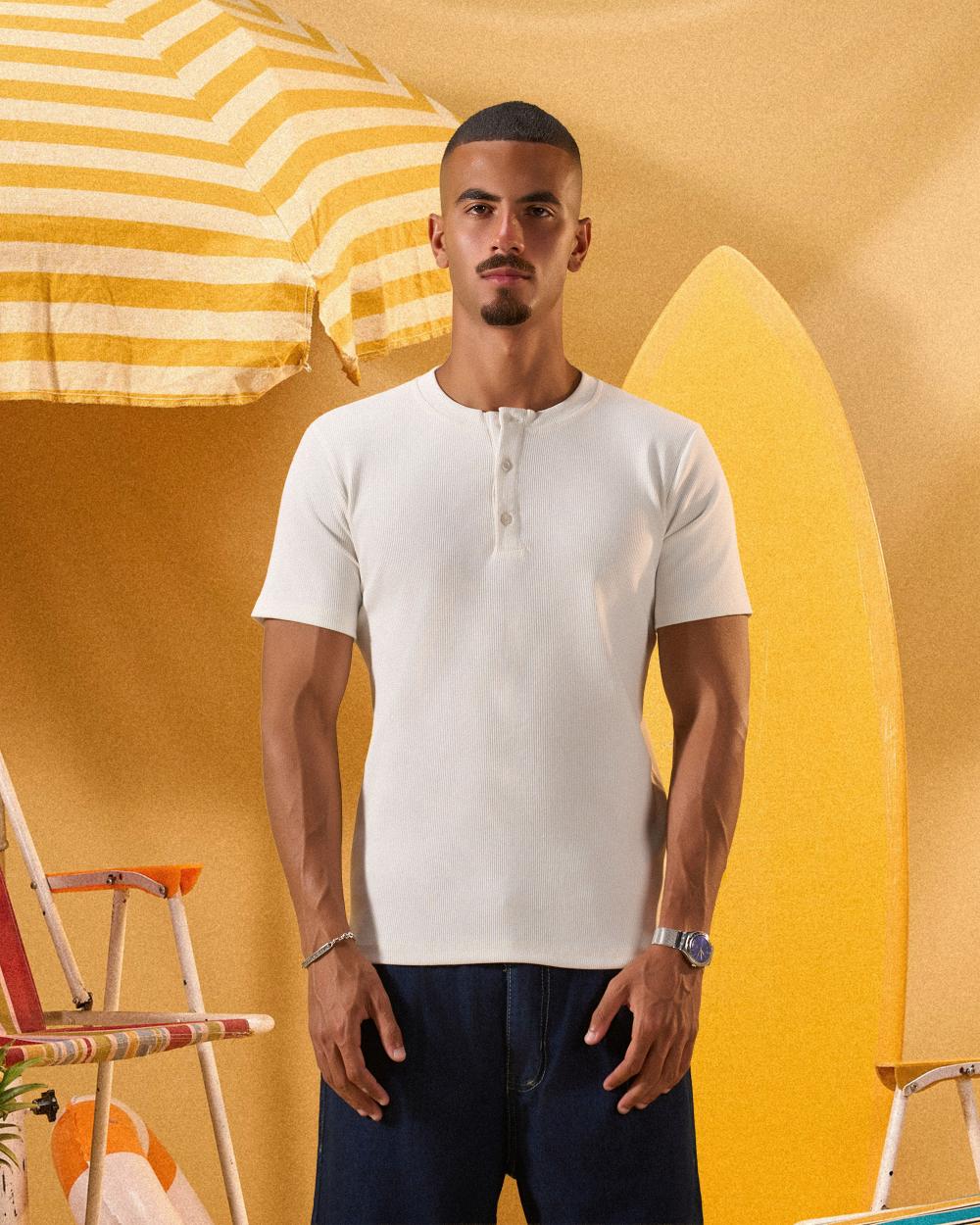 a male wearing  an off white t-shirt with buttons at the top that is a ribbed material 