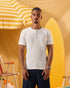 a male wearing  an off white t-shirt with buttons at the top that is a ribbed material 