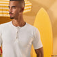 a male wearing  an off white t-shirt with buttons at the top that is a ribbed material 