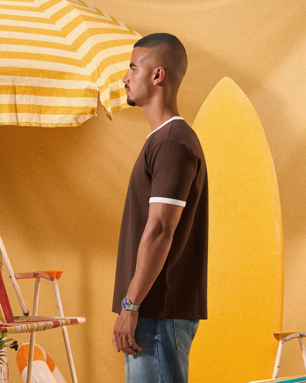 a man wearing a brown  t-shirt with contrast white neckline and sleeve trim 
