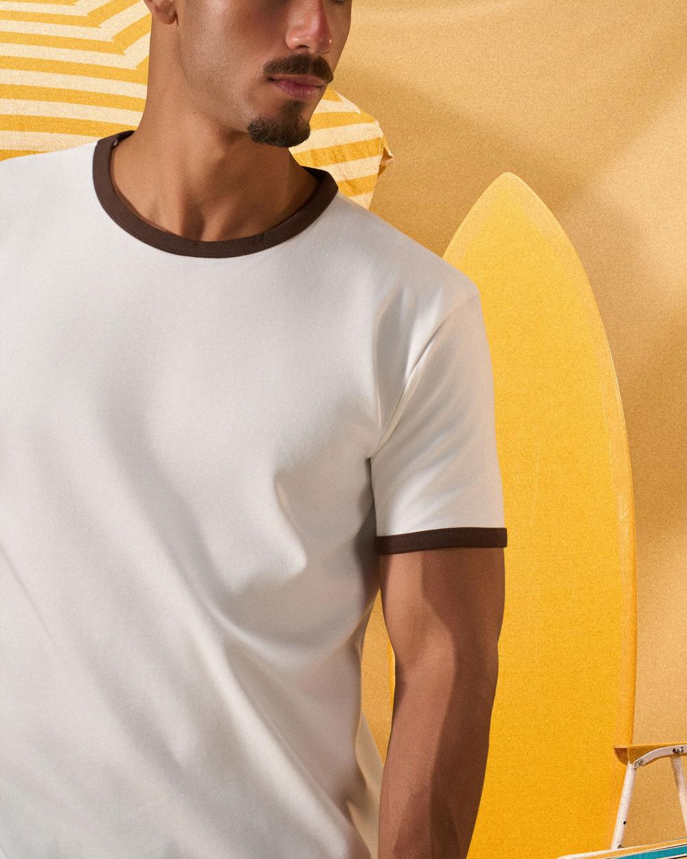 a man wearing an off-white t-shirt with a contrast brown neckline and sleeve trim 