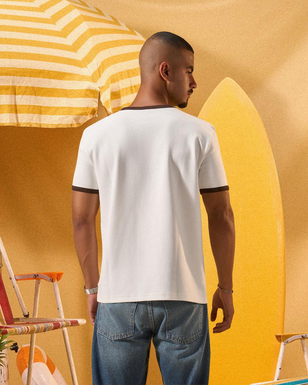 a man wearing an off-white t-shirt with a contrast brown neckline and sleeve trim 